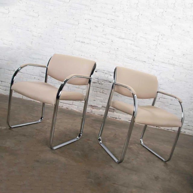 Handsome pair of modern chrome accent or dining armchairs with an off-white gaberdine-like fabric upholstery. They are in...