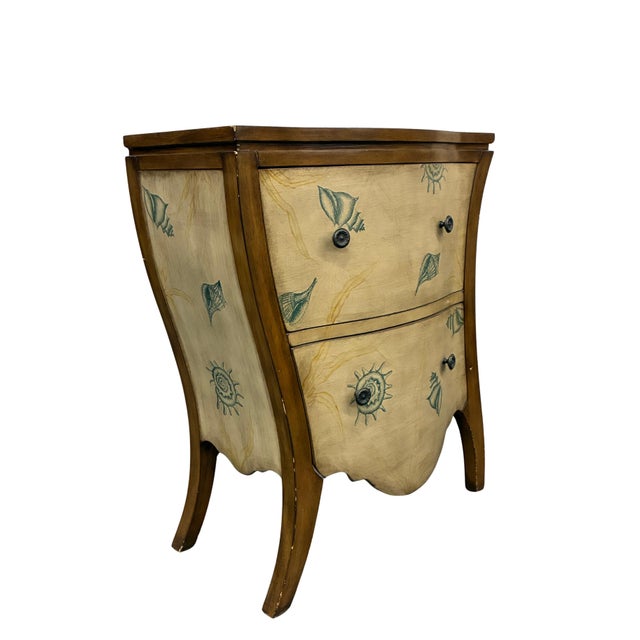 Charming vintage two-drawer accent chest featuring a dramatic bombé-inspired silhouette and whimsical coastal seashell...