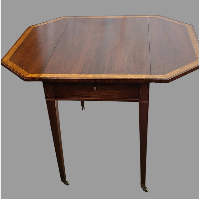 This antique drop leaf table is a true gem from the Sheraton style of English furniture. Made from high polish rosewood,...