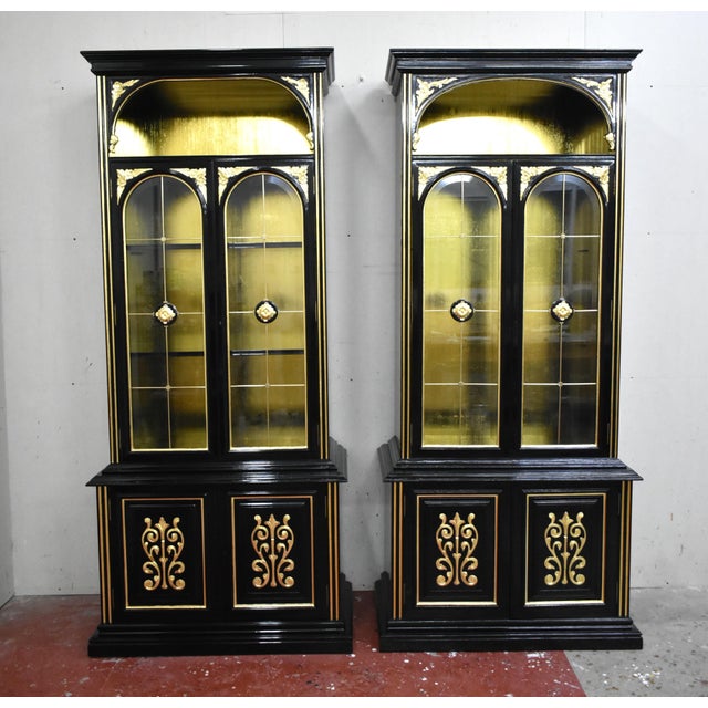 Set of two tall display cases, composed of glass upper bodies and lower modules with doors. The interior has been covered...