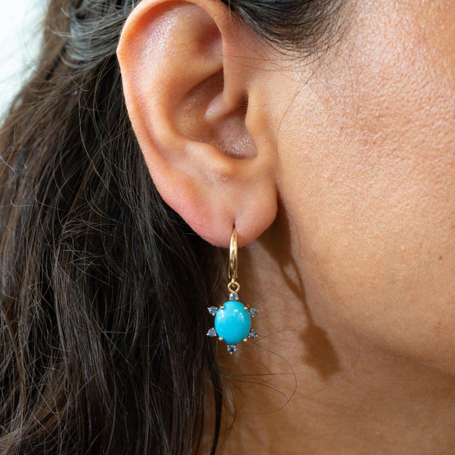 A pair of Sonoran turquoise cabochons glows in rich blue on these solid 14K yellow gold lever-back earrings, each framed...