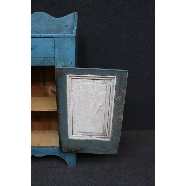 Country-style wooden milk cupboard finished in distressed turquoise blue paint. The single door features a hand-painted...