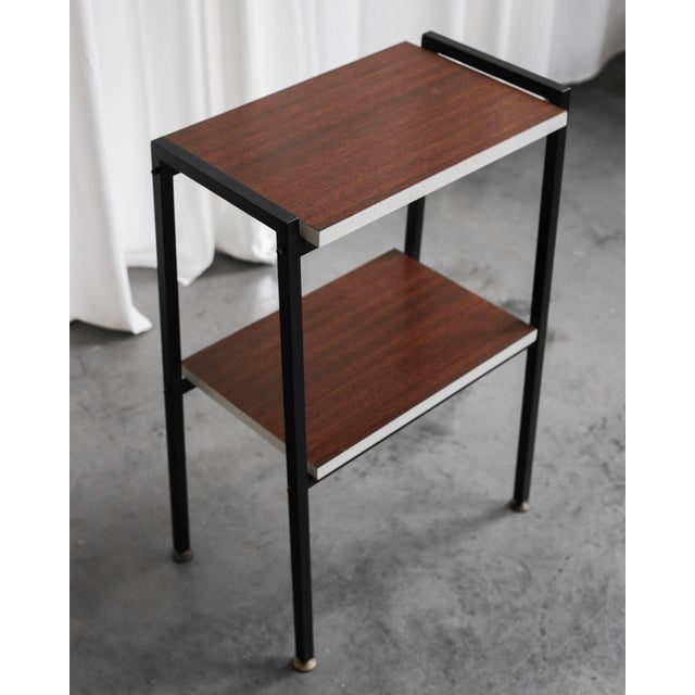 The side table comes from Italy, has a black metal structure, two wooden storage surfaces with white trim. The ends of the...