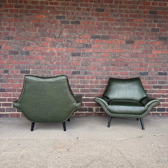 A striking pair of sculptural mid-century modern lounge chairs featuring dramatic winged forms and low, architectural...