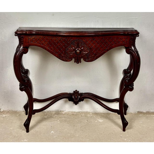 Elegant early 20th century console table crafted in richly carved wood with a beautifully shaped silhouette. The piece...