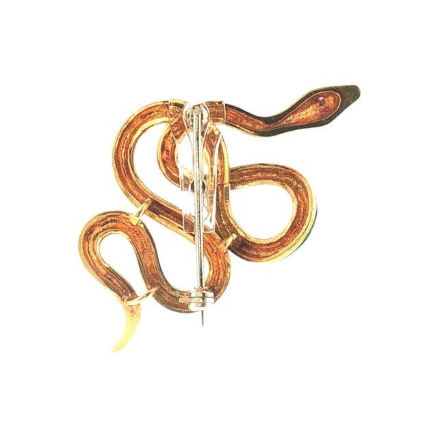 A mid-century Italian 18k gold snake brooch with intricate green and blue enamel detailing. The head features ruby eyes....