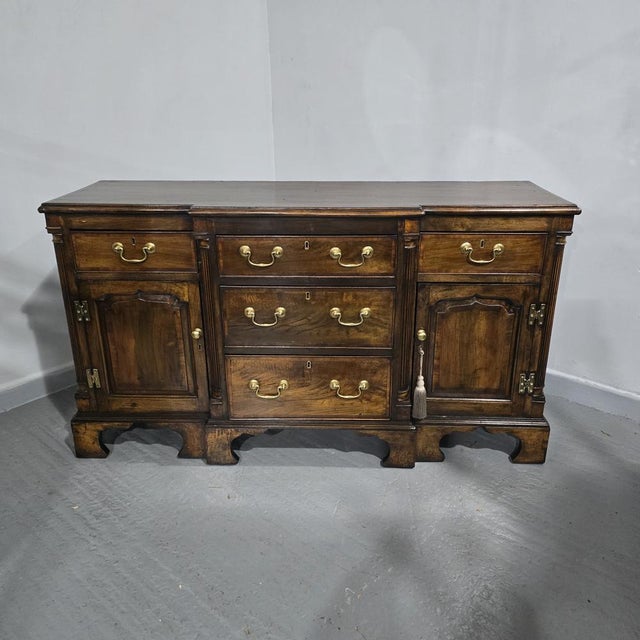 A very good walnut and mahogany crossbanded breakfront dresser base, standing on bracket feet, three central drawers with...