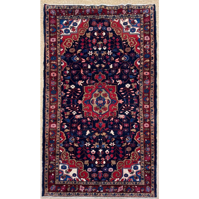 Hand-knotted rug from the Hamadan region of western Iran, featuring a large central medallion set within a dark navy...