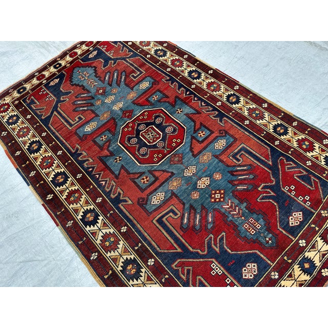 This antique hand-knotted Lori Pambak Kazak rug features a monumental stepped cruciform medallion in slate blue, anchored...