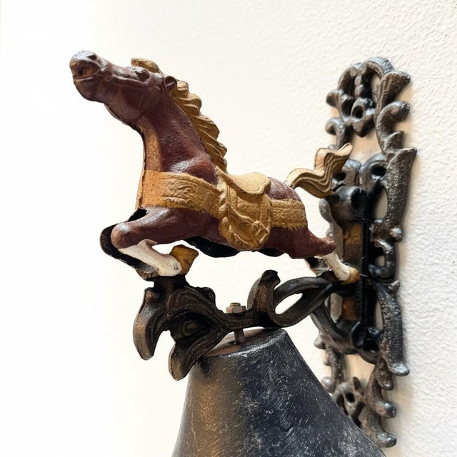 Antique cast iron wall-mounted bell featuring a spirited horse in motion, a design popular in late 19th to early 20th...