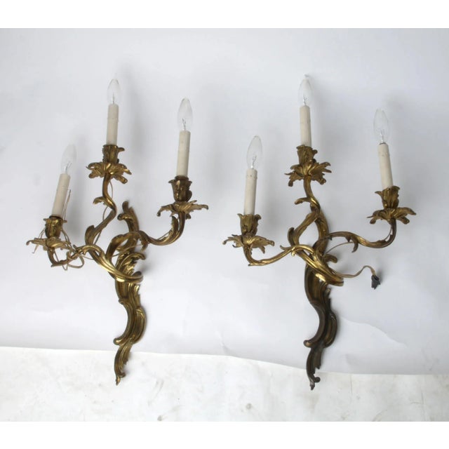 French Baroque bronze, leafy vine motif, three-arm wall sconces with candlestick lights. Wired and in working condition....
