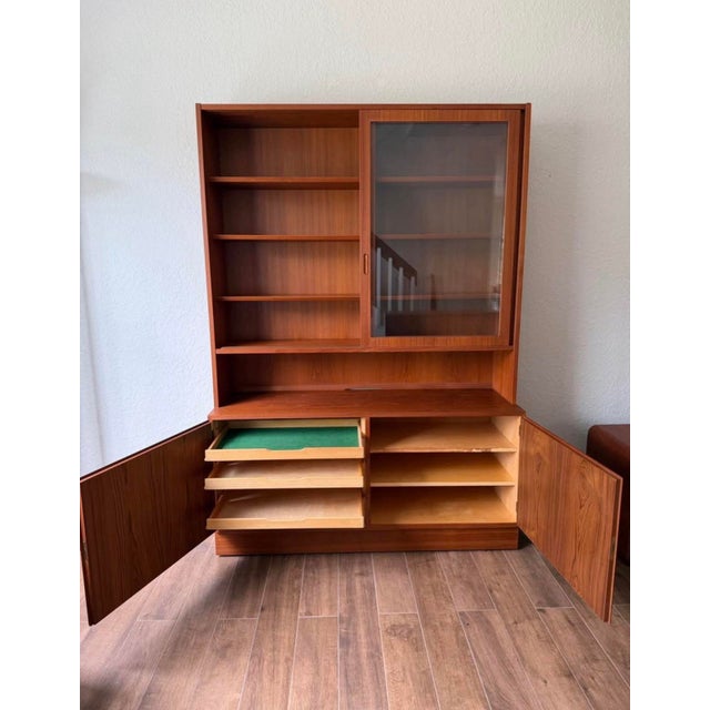 Vintage 1970s teak hutch. It has a two-piece design with a warm finish. The upper section features two sliding glass doors...