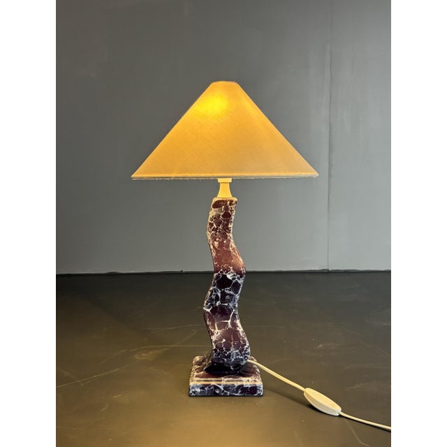 Lovely table lamp attributed to France in faux marble ( resin composite ) fitted for a general E14 lightbulb, 1980s. The...