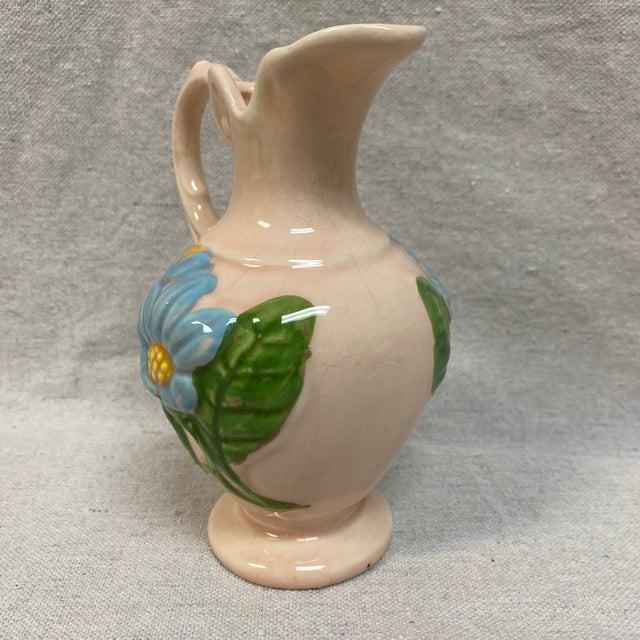 Made by Hull pottery art, it features a glossy pink background with a hand-painted blue magnolia flower and green leaves.