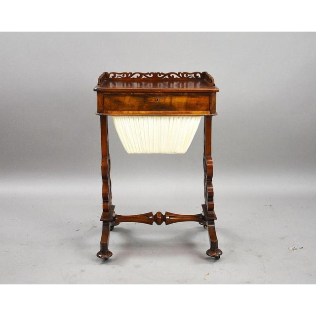 A decorative Victorian mahogany work table, raised on elegant pierced end supports with shaped stretcher and scrolling...
