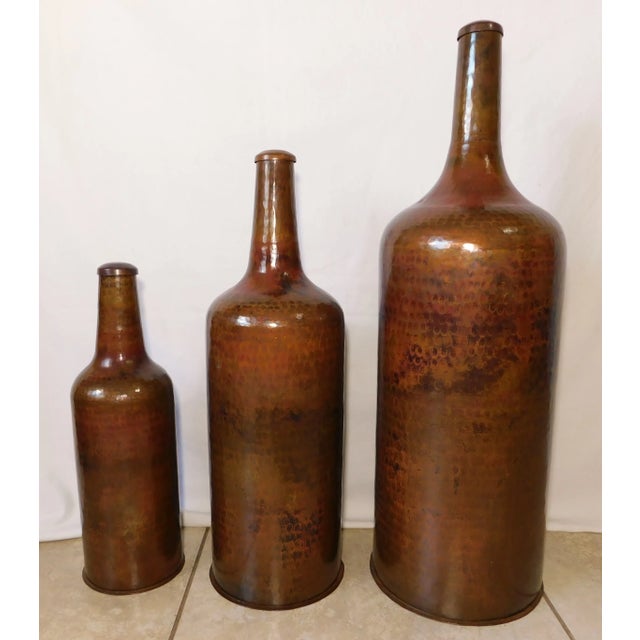 Wonderful vintage decorative set of three graduating hand hammered solid copper bottle decanter floor vases. They range in...