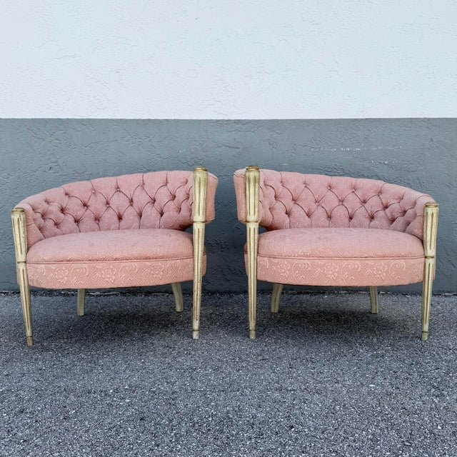Glamorous pair of vintage French-inspired barrel chairs featuring softly curved silhouettes upholstered in blush pink...