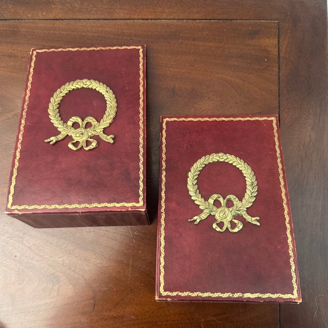 Listing is for a pair of deep red leather book ends with gilt embossed borders and large brass Laurel wreath in center....