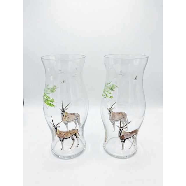 Add a touch of exotic elegance to your home decor with this striking pair of hand-painted hurricane glass vases. Crafted...