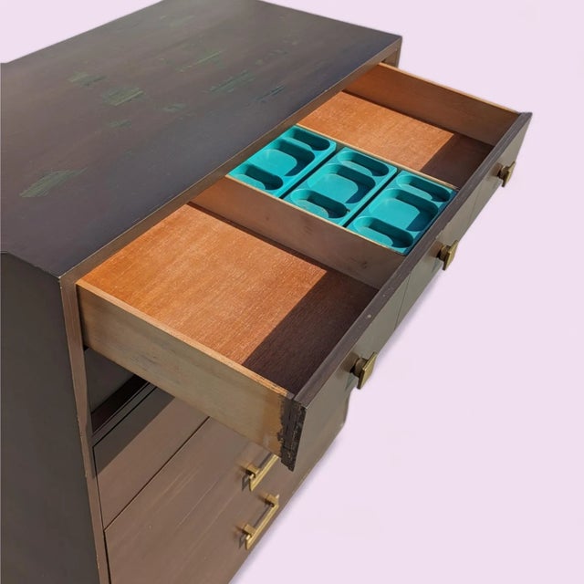 Mid-Century Modern six-drawer tallboy dresser with a warm wood finish, clean vertical proportions, and brass-tone handles....