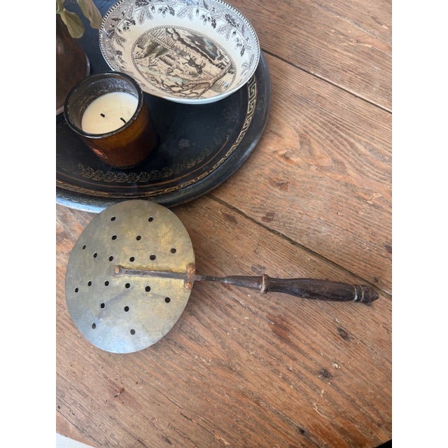A wonderful example of early kitchenware, this antique perforated skimmer features a large round metal head fitted with...