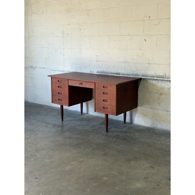 This double pedestal desk features eight side drawers and a wide central drawer. Tapered legs and recessed carved handles...