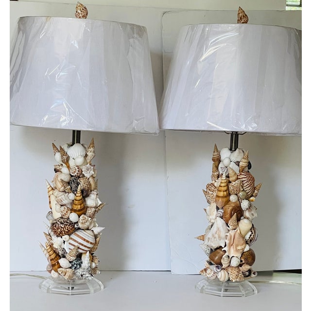 Gorgeous pair of richly encrusted with selected sea shells lamps on lucite bases. Sea shells lamp finials.