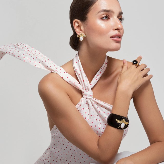 The Gigi Studs are an eye-catching piece crafted from semi-precious stones, featuring a unique insect motif in gold tones....