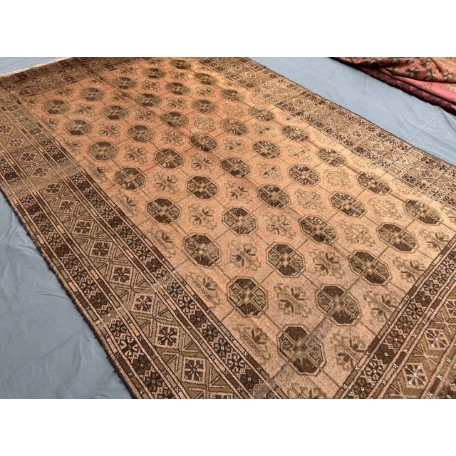 Welcome! This vintage Afghan hand-knotted tribal rug features a striking geometric design in warm brown and beige tones,...