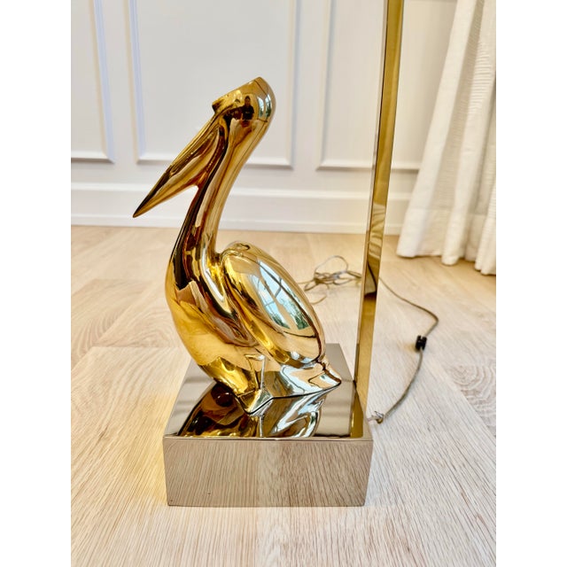An incredible vintage modernist table lamp featuring a highly stylized brass pelican sculpture mounted on a polished...