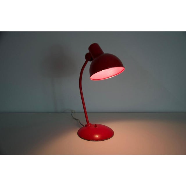 This striking red desk lamp is an original piece from the 1960s, crafted in germany by the renowned manufacturer kaiser....