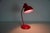 This striking red desk lamp is an original piece from the 1960s, crafted in germany by the renowned manufacturer kaiser....