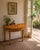 Beautiful Chelsea House demilune console table featuring a satinwood-style finish with decorative floral garland, ribbon,...