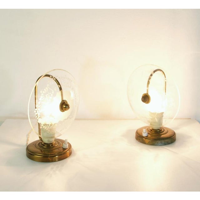 A pair of fun small lamps inteded to stand beside the bed made in brass and glass. Note that the etching on the glass is...