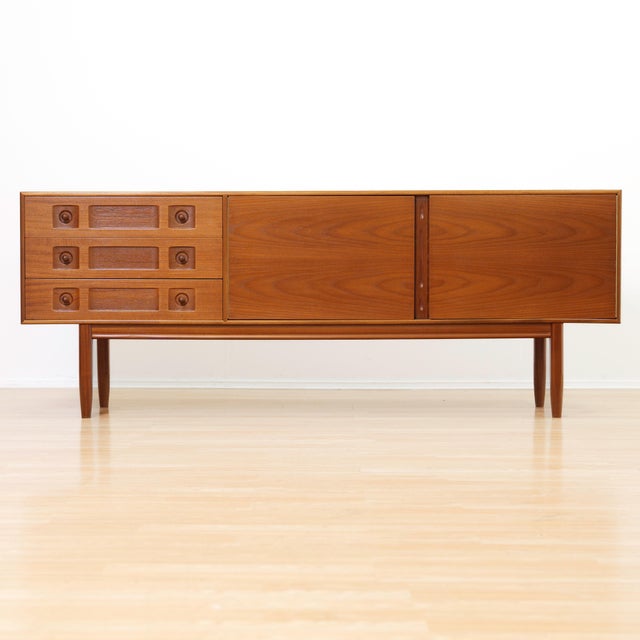 Designed and manufactured by A.H. McIntosh of Kirkcaldy, this elegant mid-century credenza showcases the refined...