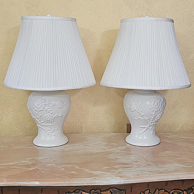 Pair of vintage American-made white ceramic ginger jar table lamps featuring raised floral relief decoration, glossy white...