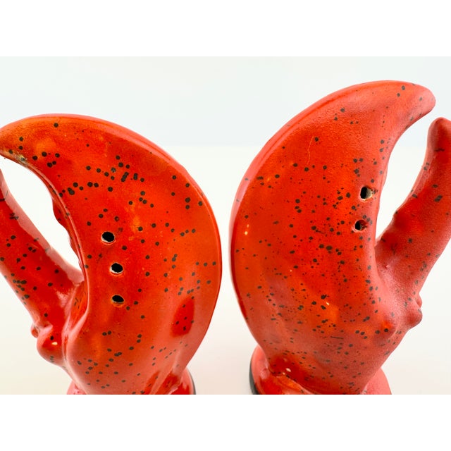 A charming pair of vintage ceramic salt and pepper shakers designed as oversized lobster claws, finished in vivid coral...