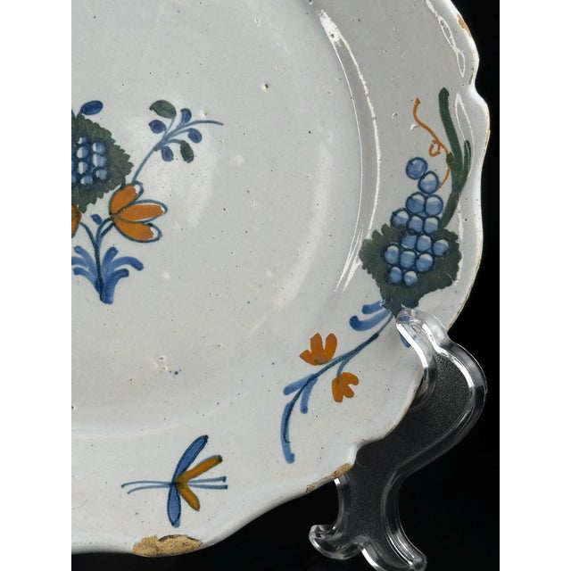 An authentic 18th-century French faience plate from La Rochelle, finely hand-painted in soft polychrome enamels with a...