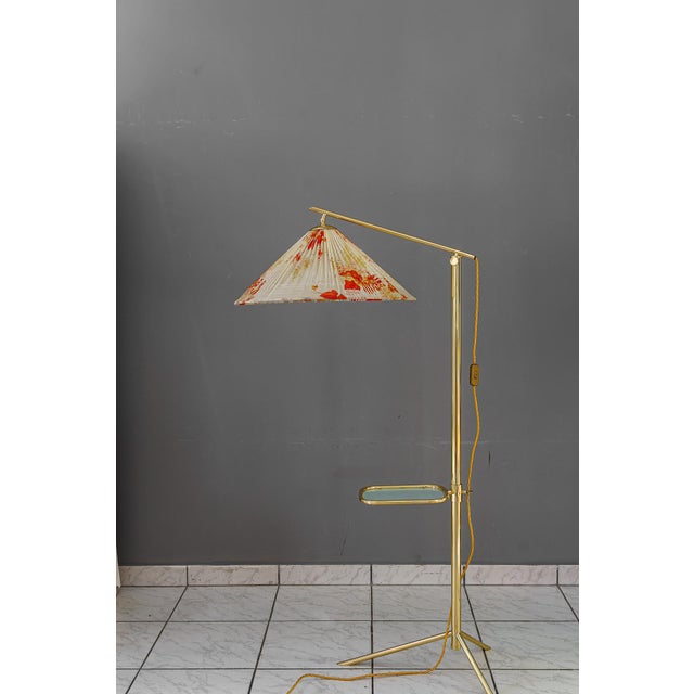 Hight adjustable Floor lamp with adjustable shelf vienna around 1950s. Brass polished and stove enameled. Original fabric...