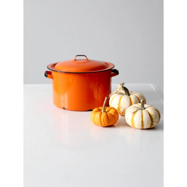 This mid-century enamelware pot features a vibrant orange finish accented by classic black trim for a bold yet timeless...