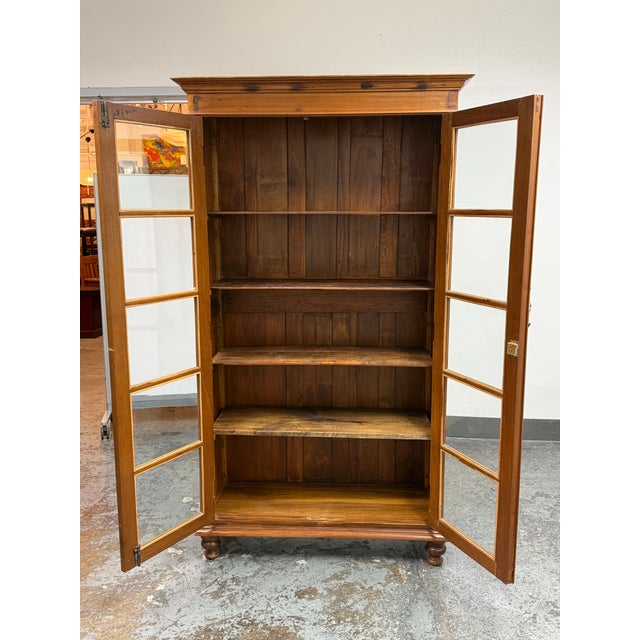 Design Plus Gallery presents a Vintage Display Cabinet. The display cabinet has a wood frame with glass-paneled double...