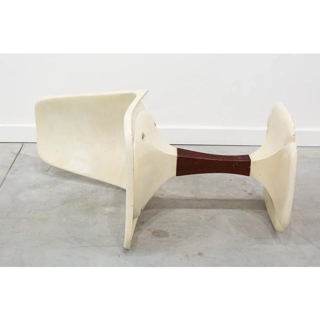 Chair made of white plastic with organic shaped seat and a single central foot finished in poly-lobed base with wooden...