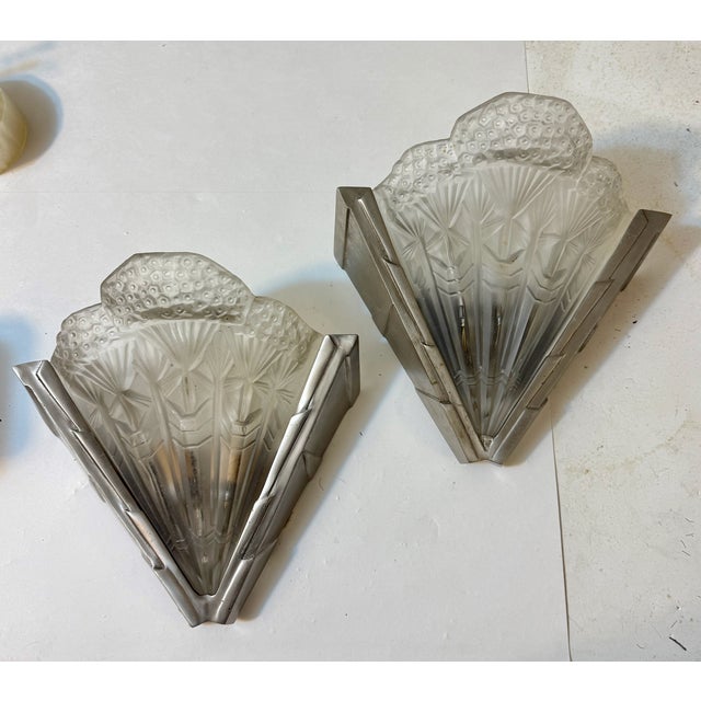 Pair of French Art Deco sconces signed "Noverdy France”. Clear frosted glass shades with intricate geometric details. Held...