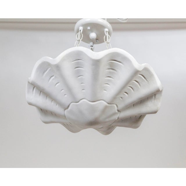 A plaster pendant in an undulating shell shape, with scalloped edges and imprinted lines accentuating the form. A newer...