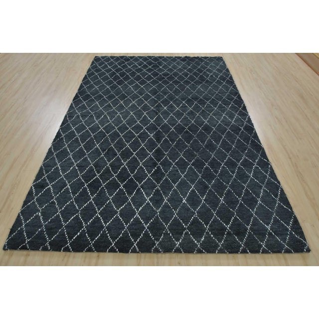 A contemporary Moroccan rug hand-knotted with an all-wool pile on a cotton foundation. This plush area rug features an...