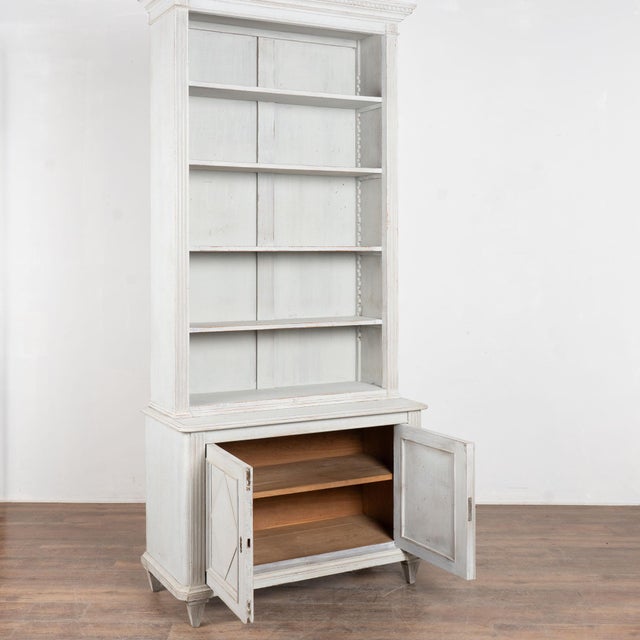 19th century Swedish gustavian style bookcase or display cabinet, crafted in pine. The top crown is accented with carved...
