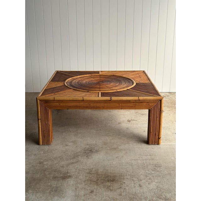 Vintage monumental square rattan coffee table with a concentric sunburst top and wrapped bamboo frame. Hand-pinned...