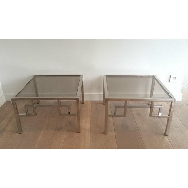 This pair of design side tables are made of chrome with a glass piece on top. They have Greek key decors on front. This is...