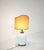 Elegant porcelain or ceramic table lamp featuring a white base with embossed decorations and a gold lampshade. The design...