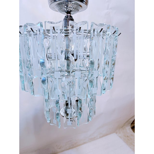 This is a 1970's art deco chandelier with etched glass panel and chrome frame. It has 8 sockets that use a candelabra...